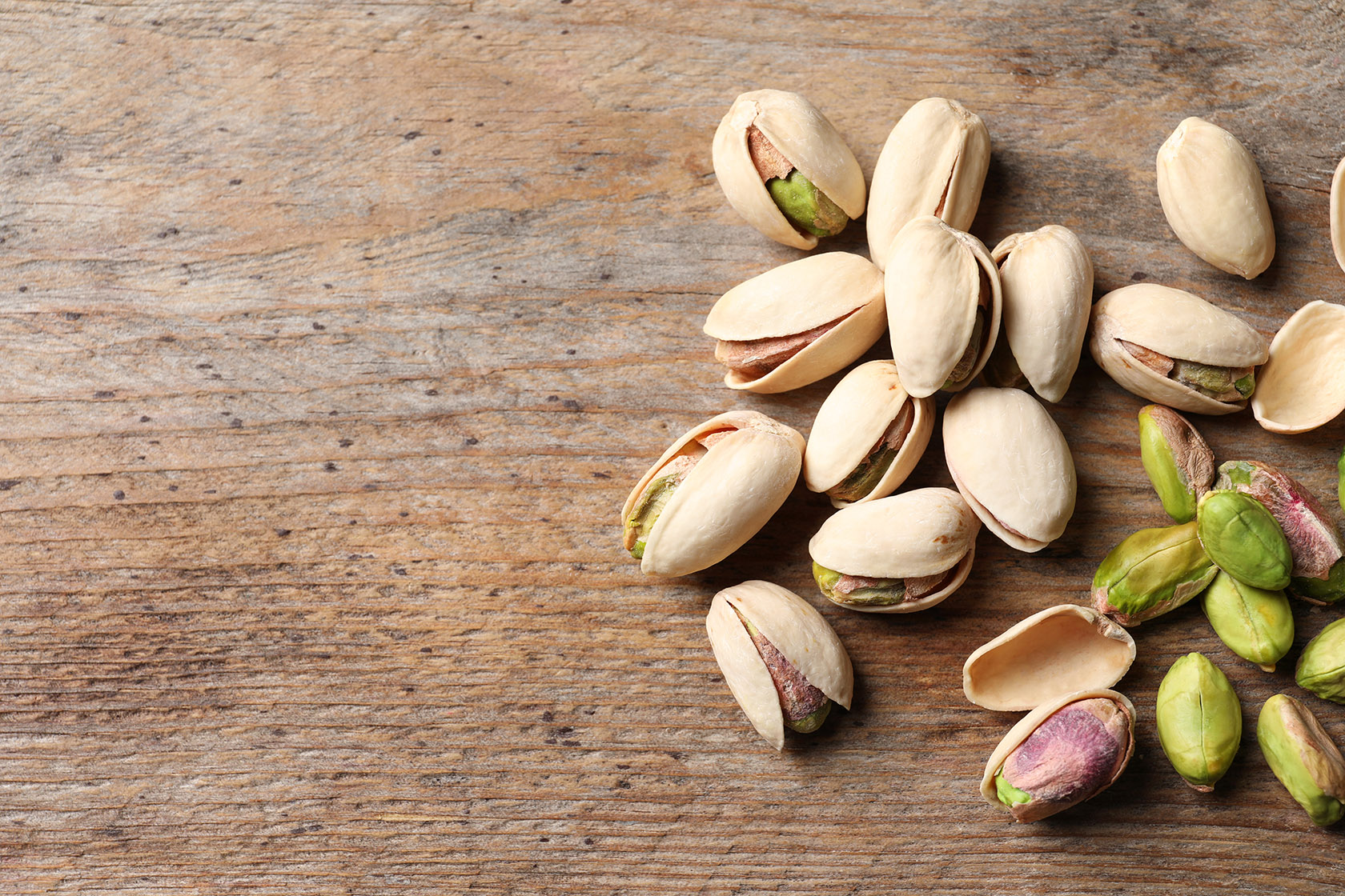 Organic pistachio nuts on wooden table. Space for text